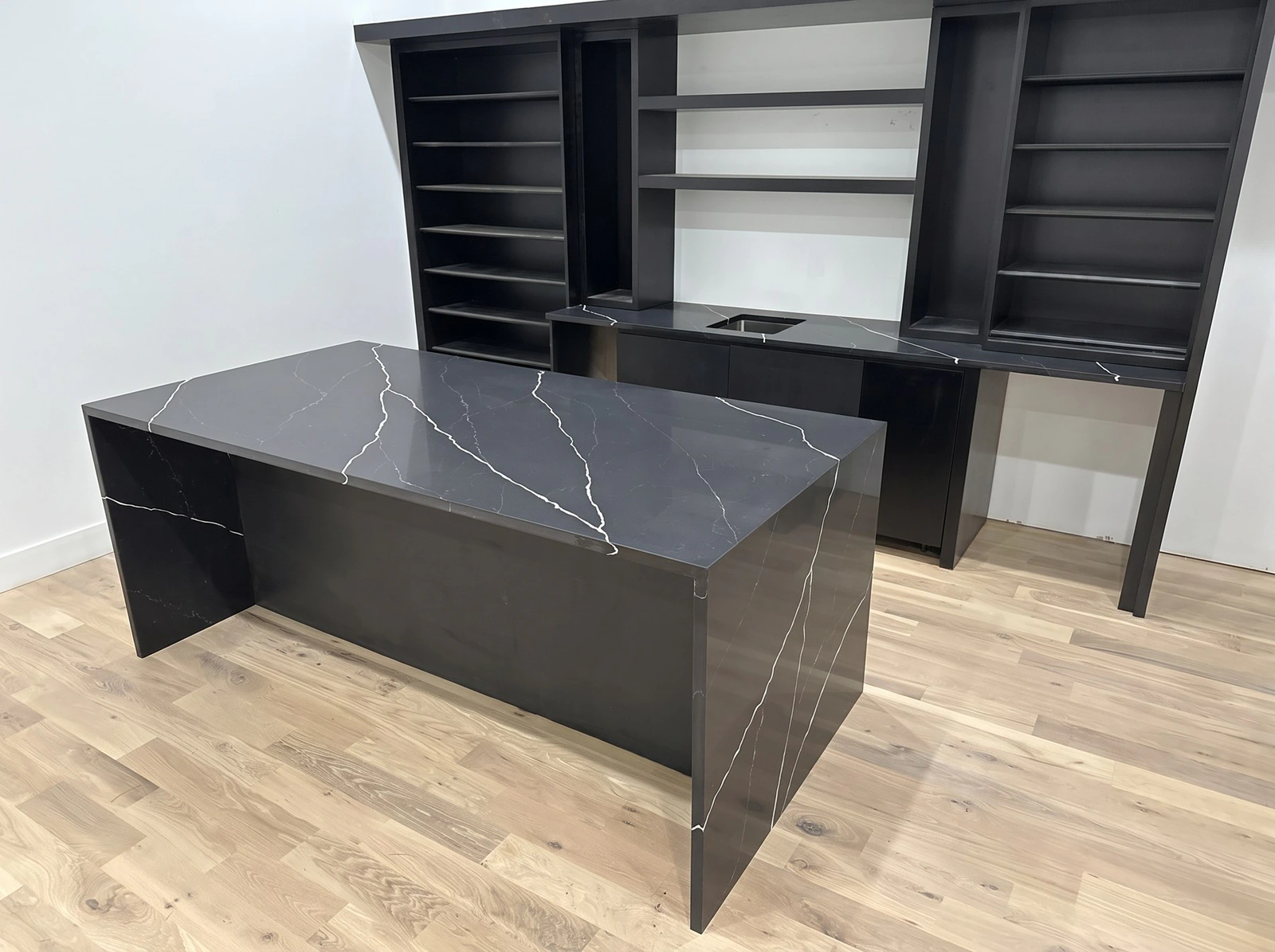 Black stone waterfall island with white veining in a basement bar