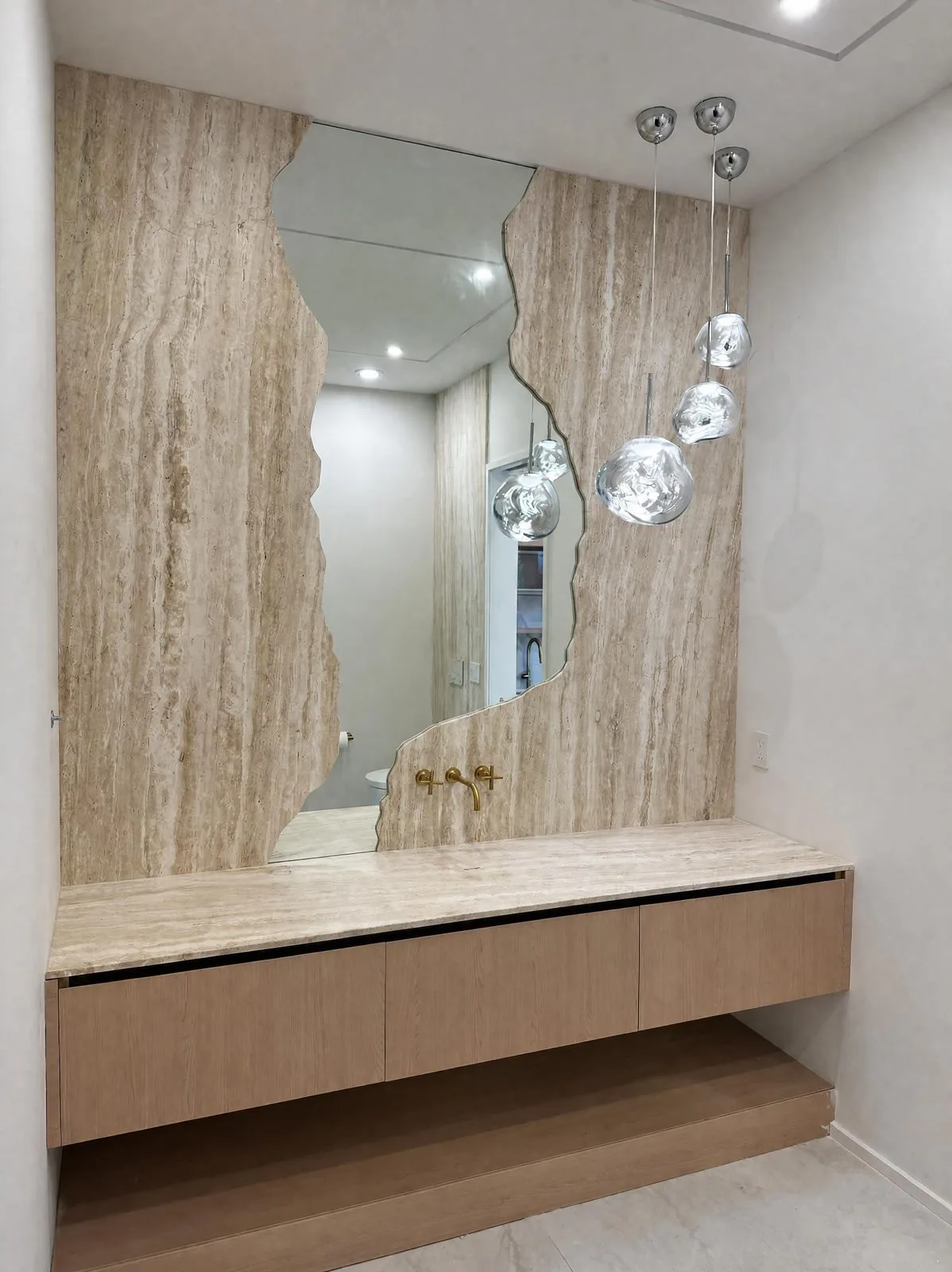 Powder room with a sculpted mirror cut in Travertine