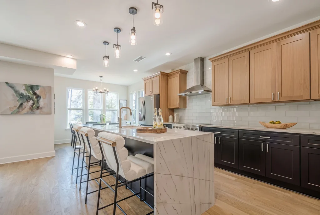 Kitchen with a white quartzite waterfall island, oak upper cabinets and black lower cabinets