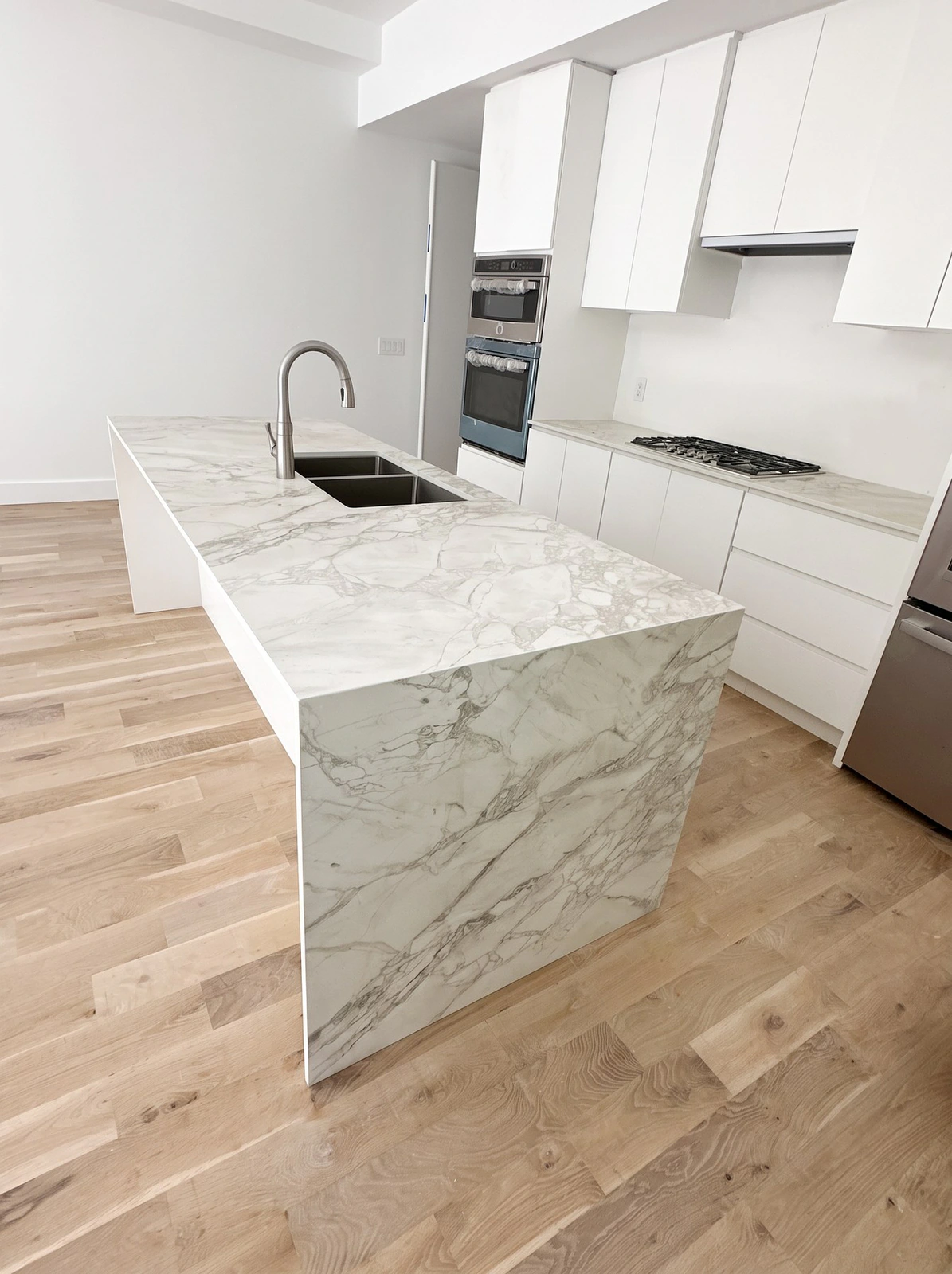 Stone waterfall island in a white upstairs kitchen