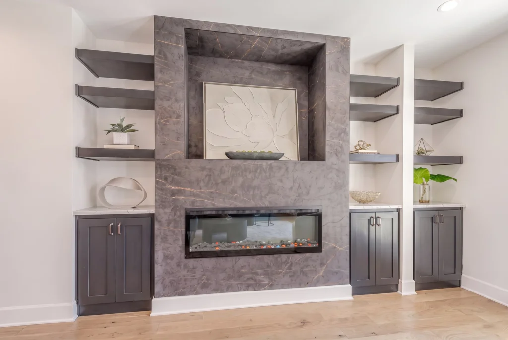 Floor-to-ceiling dark veined stone fireplace wall with a linear fireplace, art niche and built-in shelves